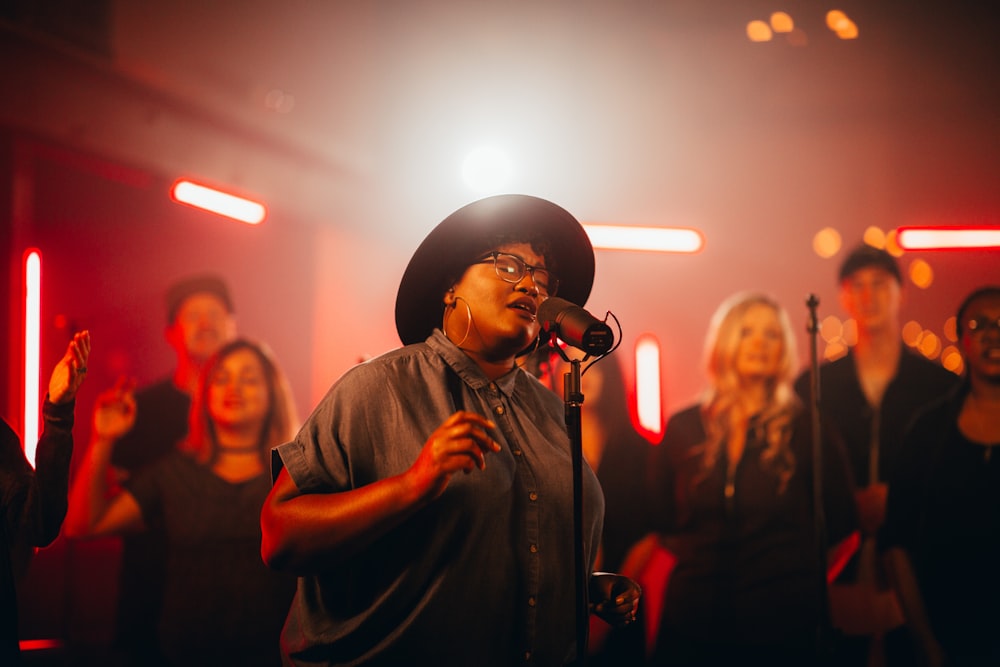 a woman singing into a microphone in front of a group of people