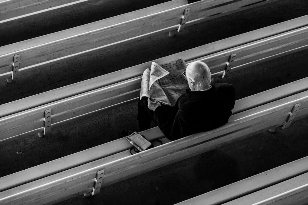 a man sitting on a bench reading a newspaper