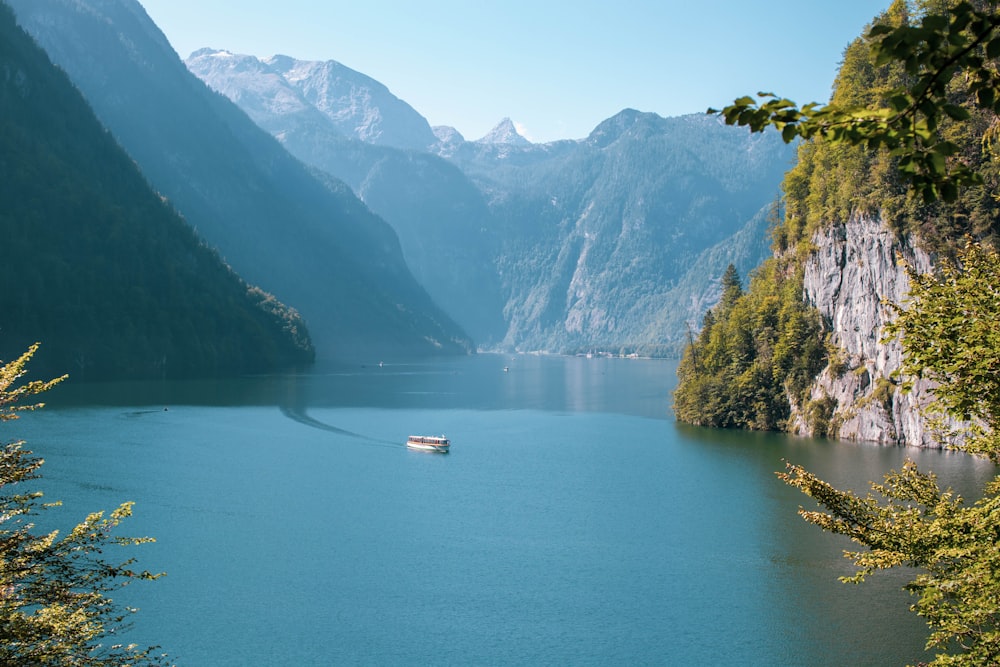 a boat floating on a lake surrounded by mountains