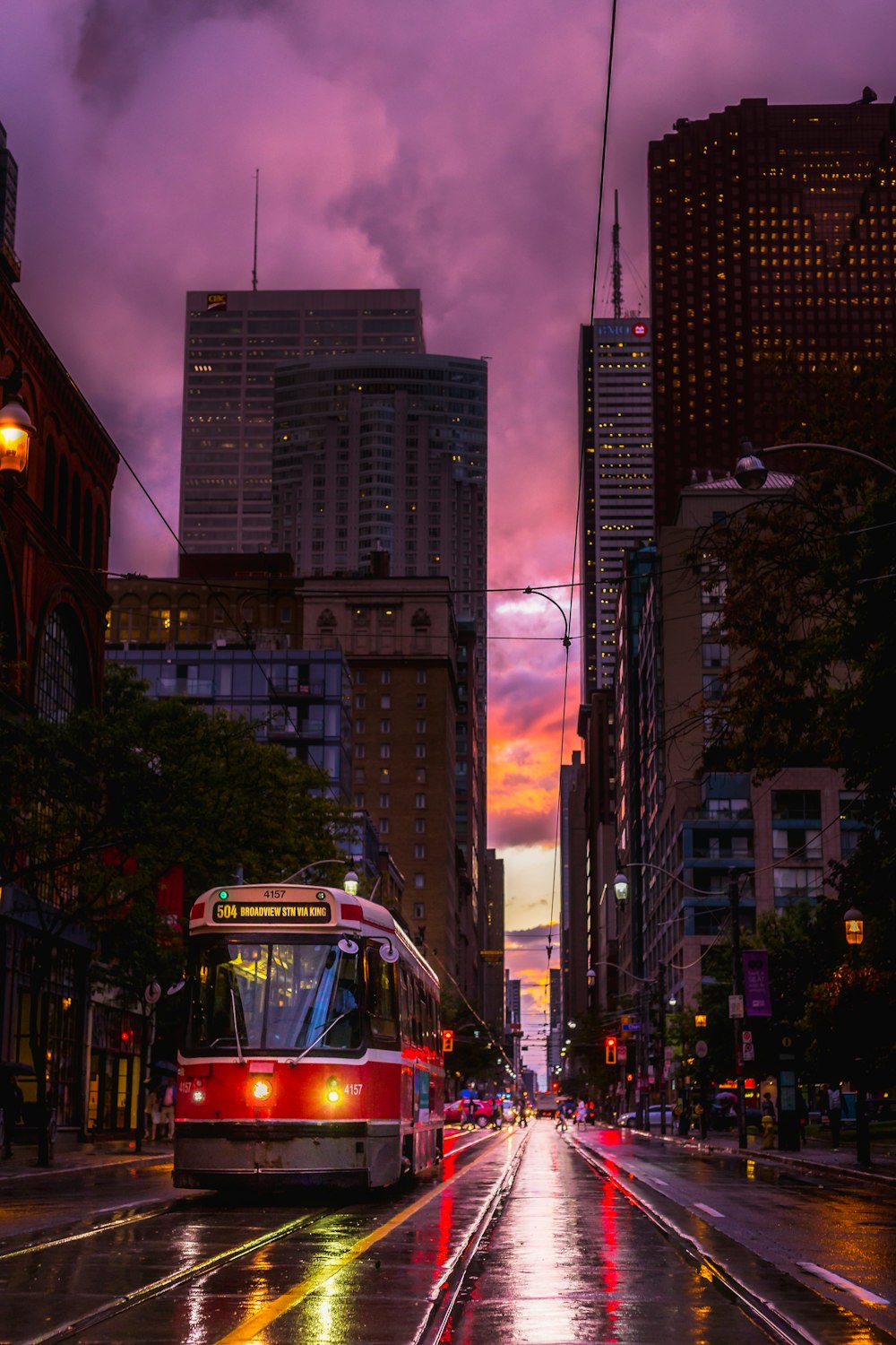 a red and white bus driving down a street next to tall buildings