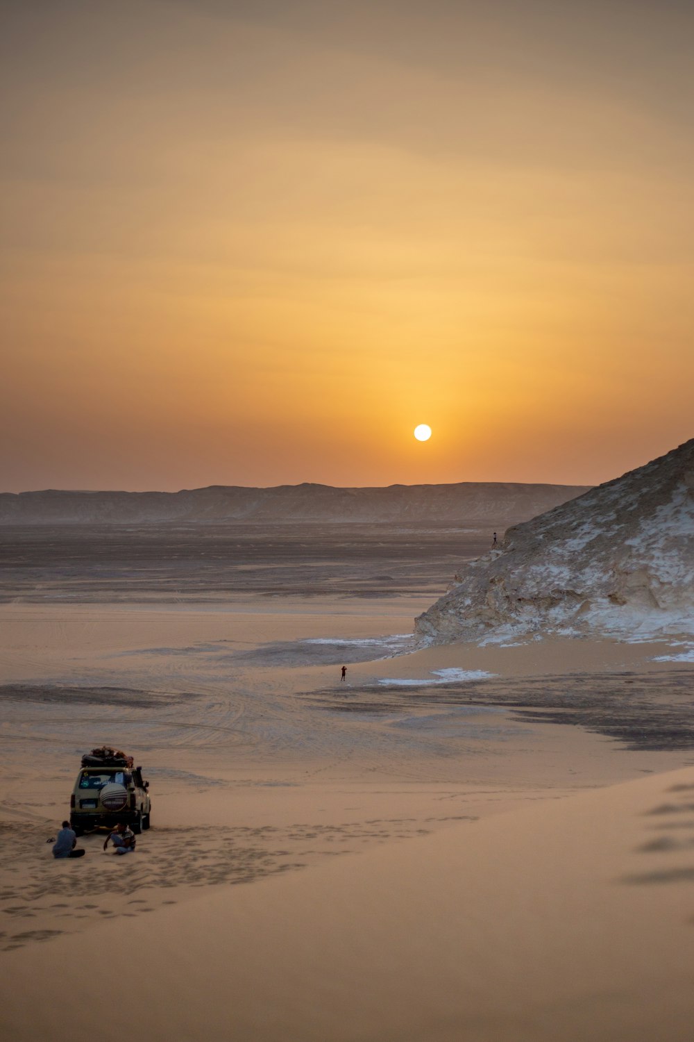 a truck is parked on the beach at sunset