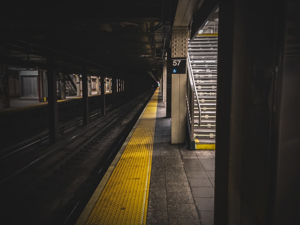 a subway station with a yellow line on the platform