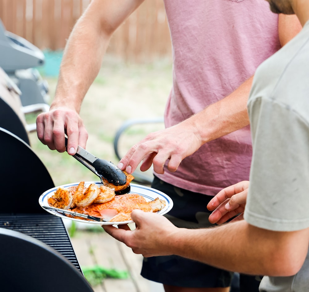 a couple of men standing over a plate of food