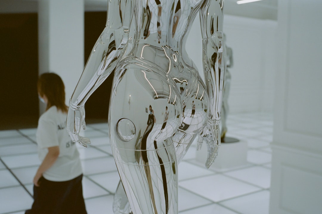 a woman walks past a sculpture of a human body, 我喜欢听人讲陌生的地方,近乎病态地喜欢。有一段时间,大概有十多年了,我从他口中听说了他的故乡和成长期间住过的地方的事。那个时候的我似乎极端想成为愿意听人讲话那一类型的人,所以无论哪一个都对我讲得十分投入。