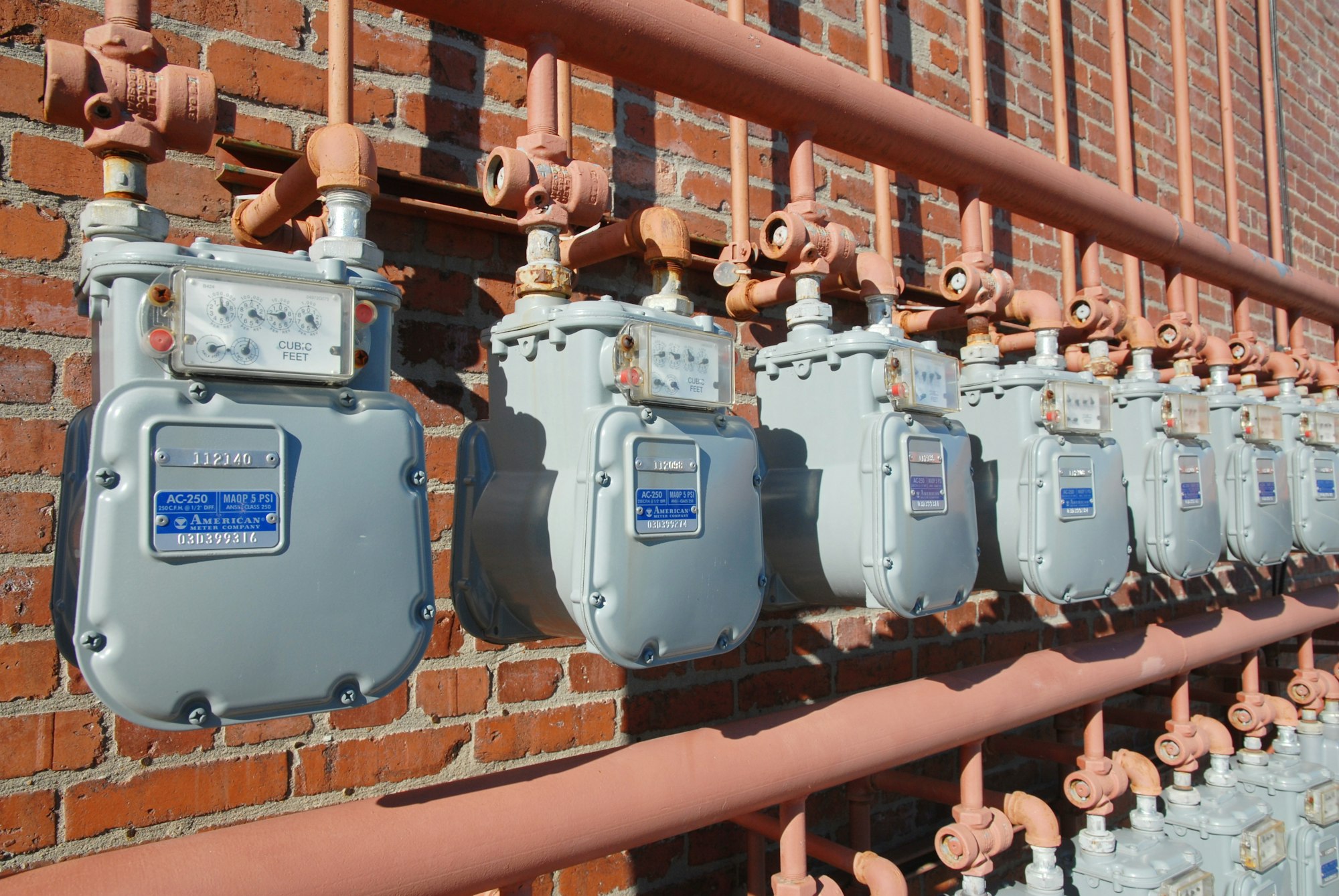 a row of electrical meters mounted to a brick wall
