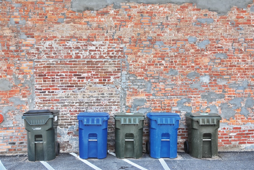 a row of trash cans sitting next to a brick wall
