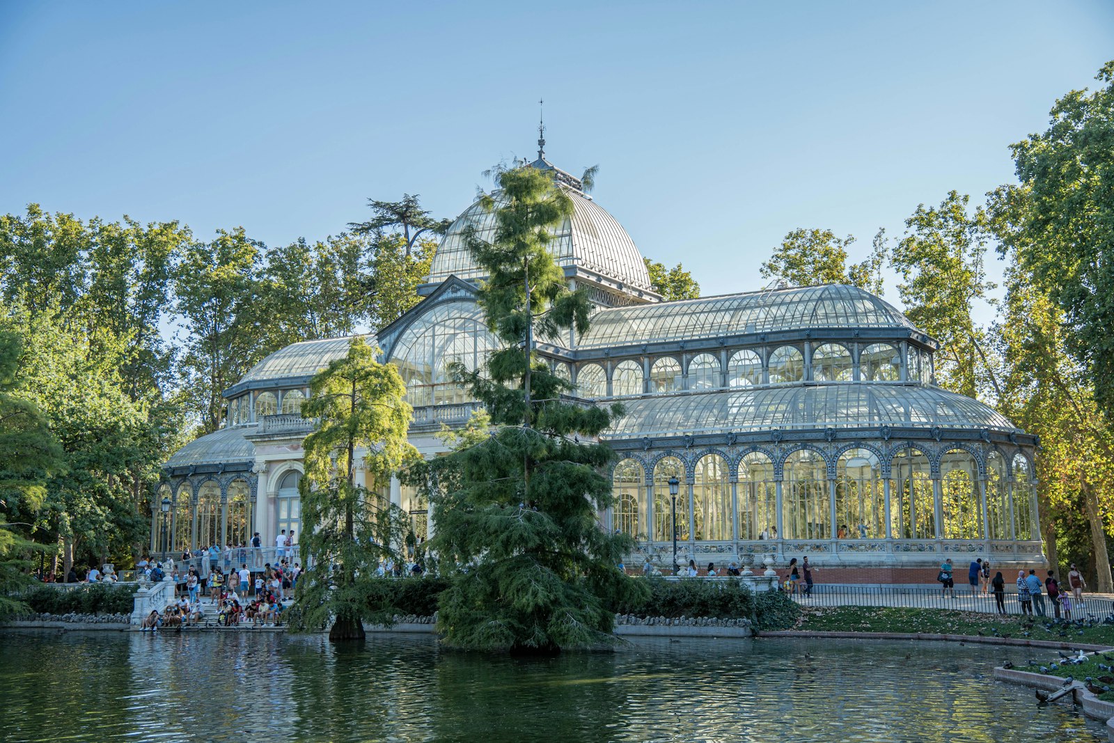 The iron-and-glass Palacio de Cristal reflected in its pond among trees in Madrid's Retiro Park
