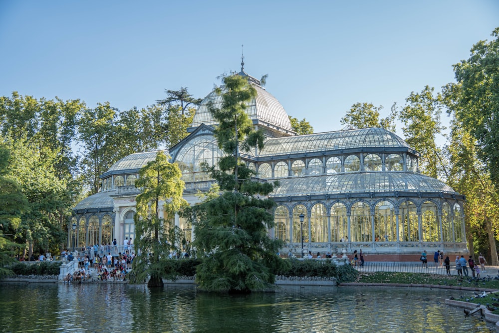 a large glass house surrounded by trees and water