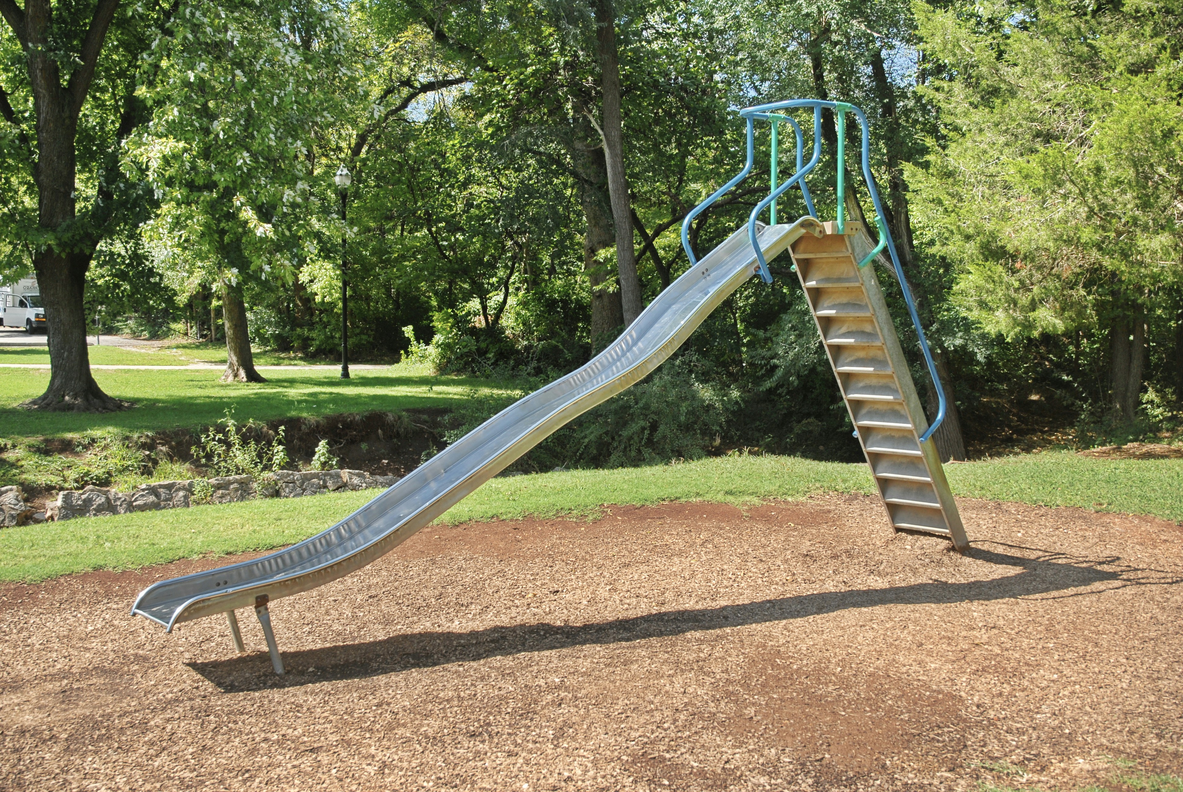 a slide in a park with trees in the background, 
