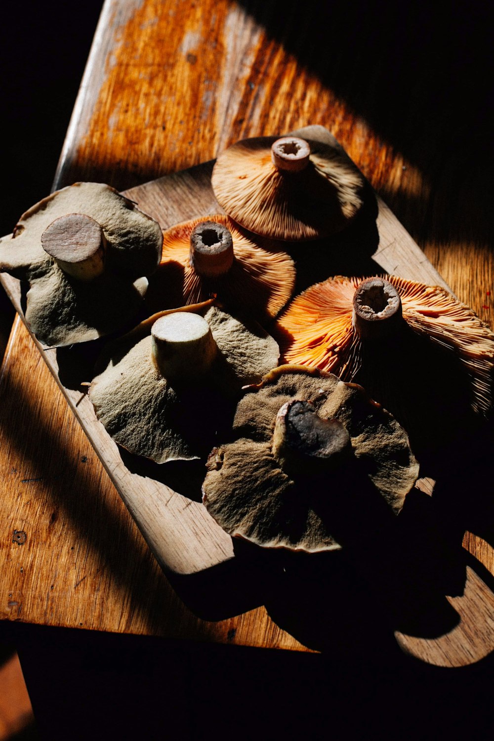 a wooden cutting board topped with mushrooms on top of a table