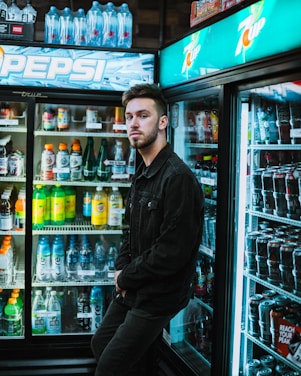 a man standing in front of a refrigerator filled with drinks
