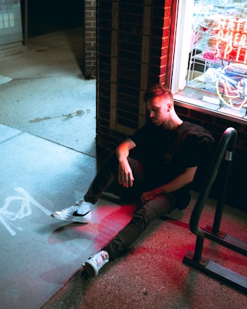a man sitting on the ground in front of a store