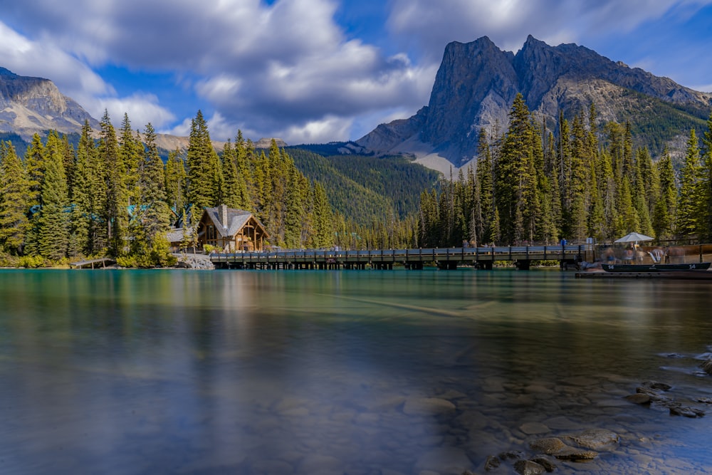 a lake surrounded by trees and mountains under a cloudy sky