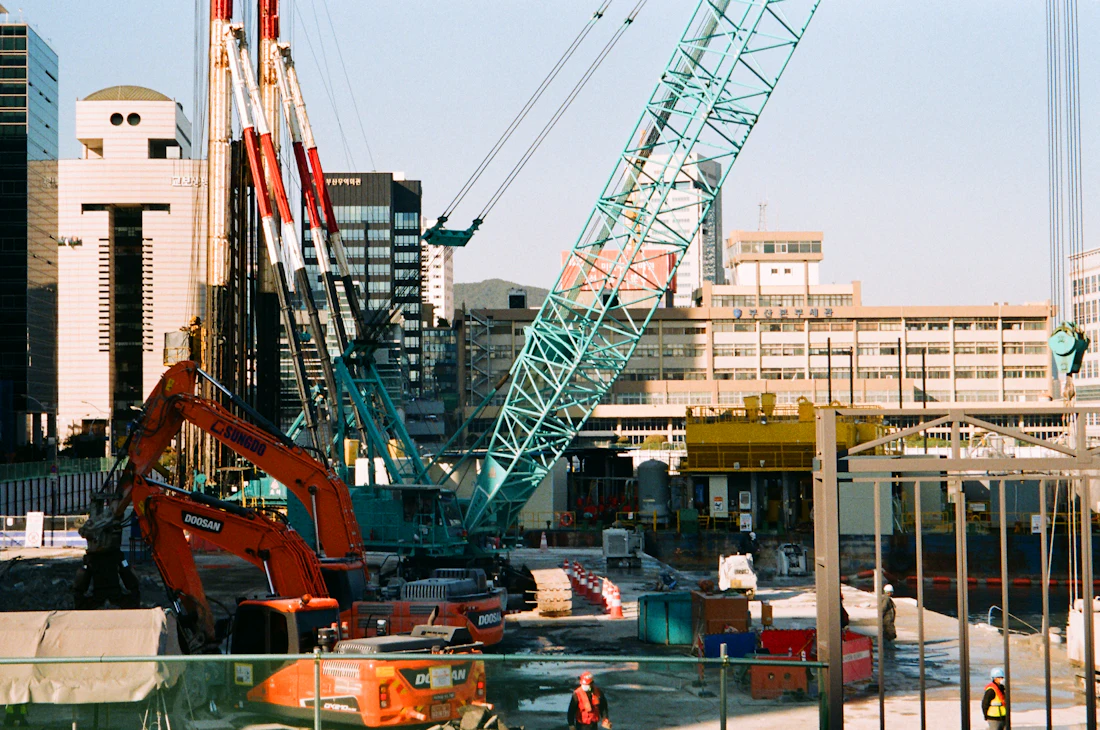 Active city construction site with excavators, a crane and hoarding
