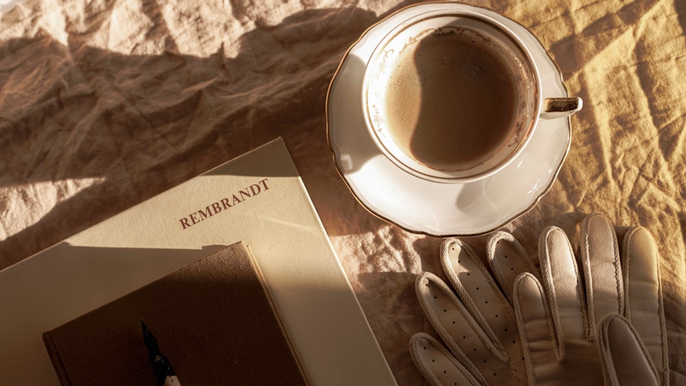 a book, gloves, and a cup of coffee on a bed