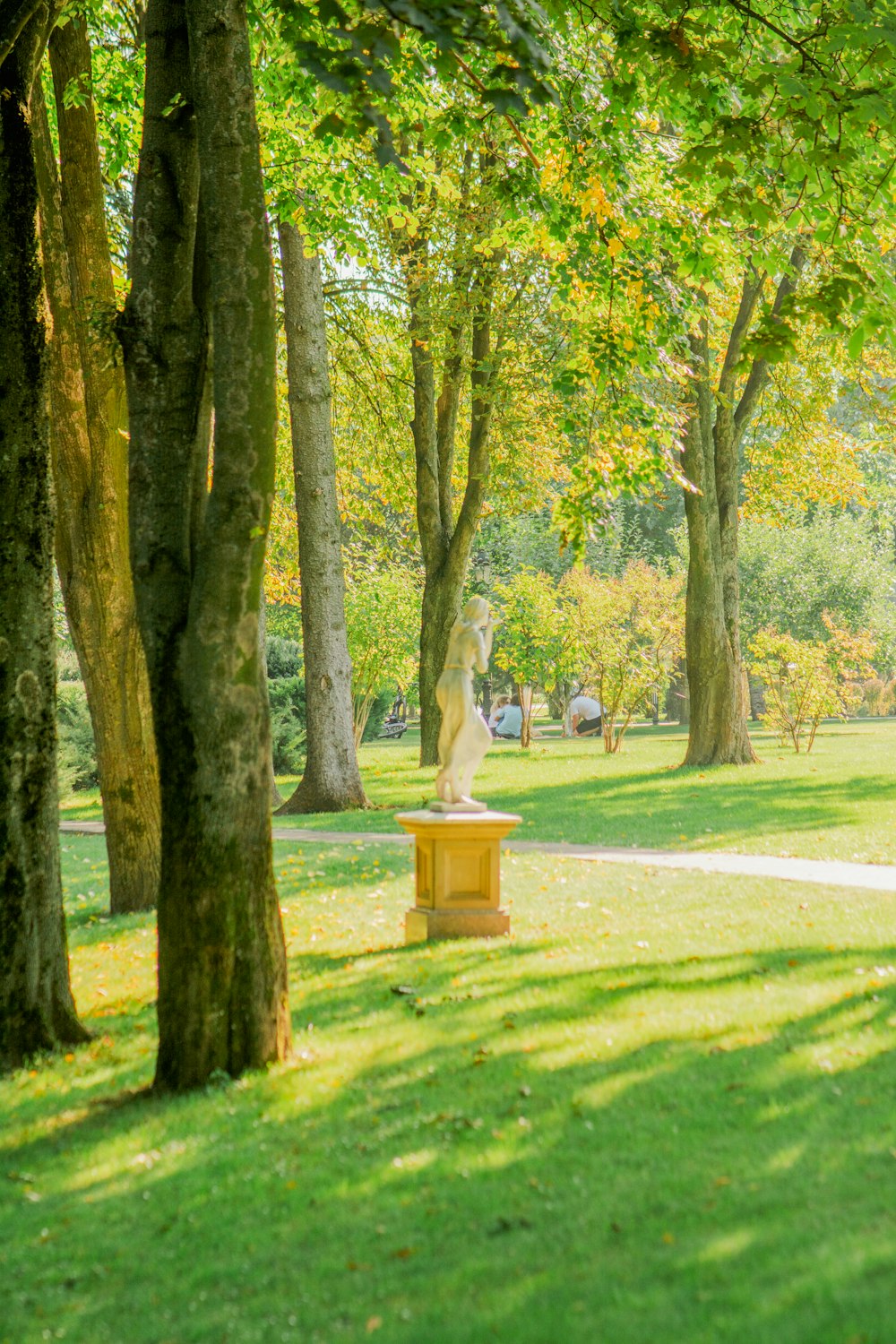 a statue in a park surrounded by trees