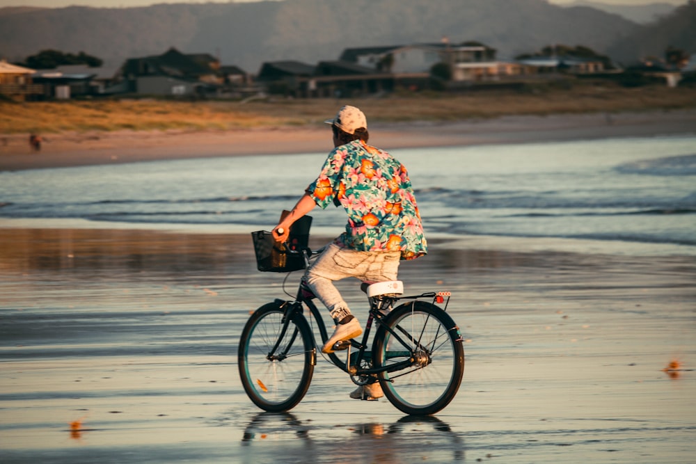 a man riding a bike down a beach next to the ocean