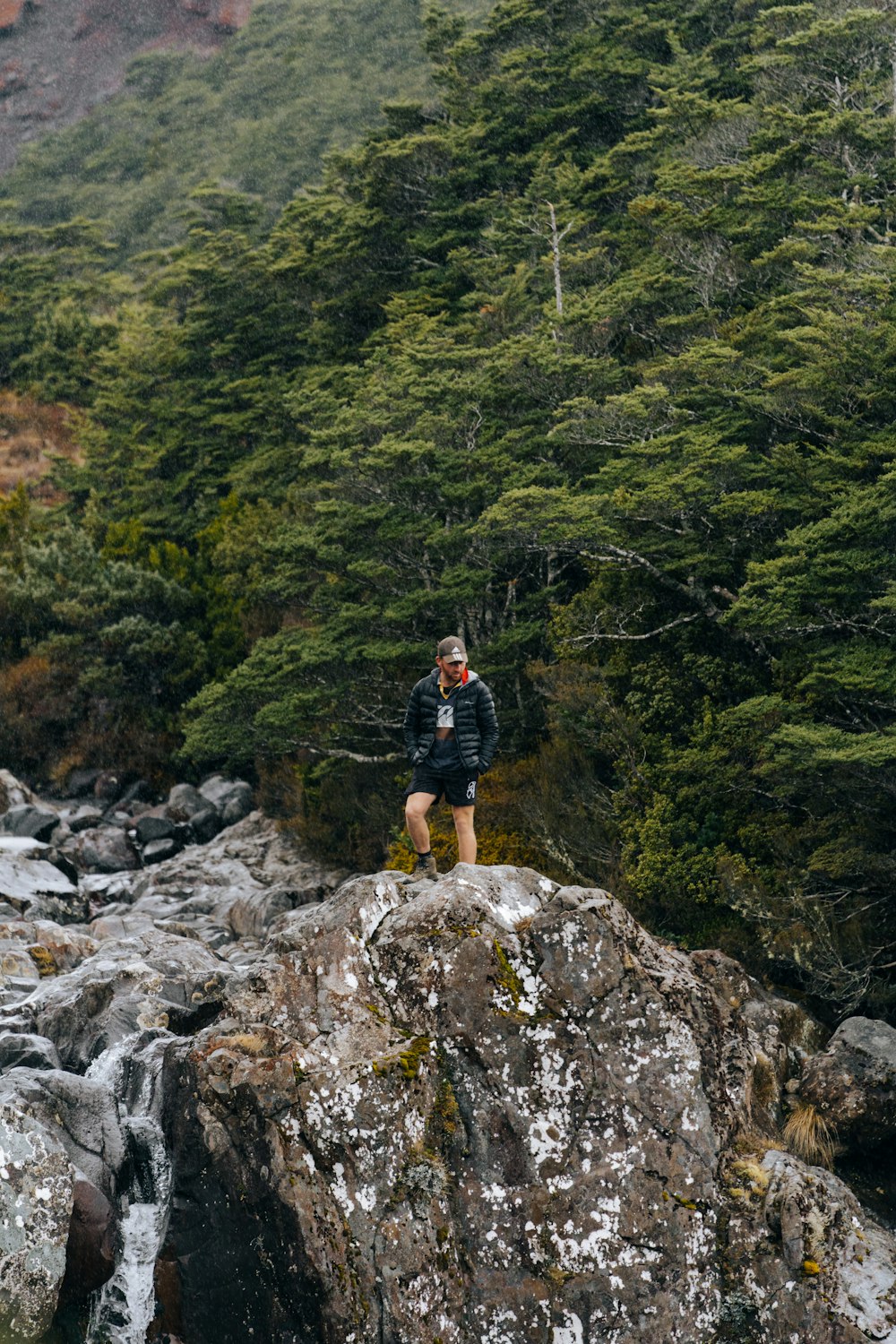 a man standing on top of a rock next to a river