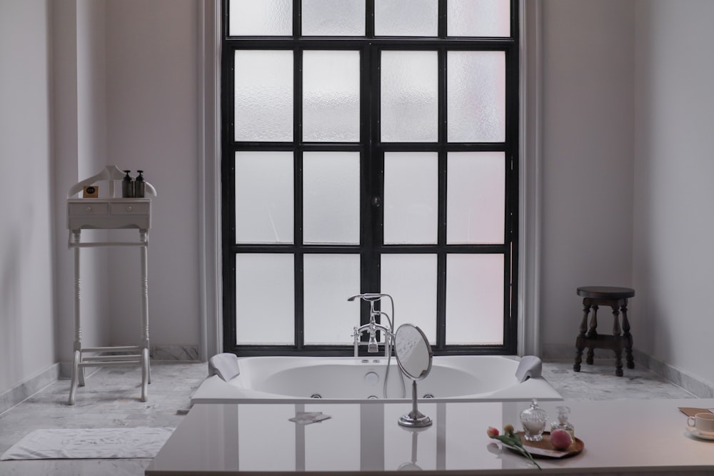 a white bath tub sitting under a window next to a sink