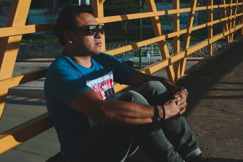 a man sitting on a yellow bench wearing sunglasses
