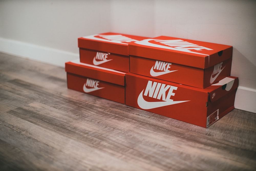 Un par de cajas rojas de Nike sentadas encima de un piso de madera