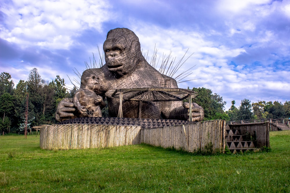 Una grande statua di un gorilla seduto in cima a un campo verde lussureggiante