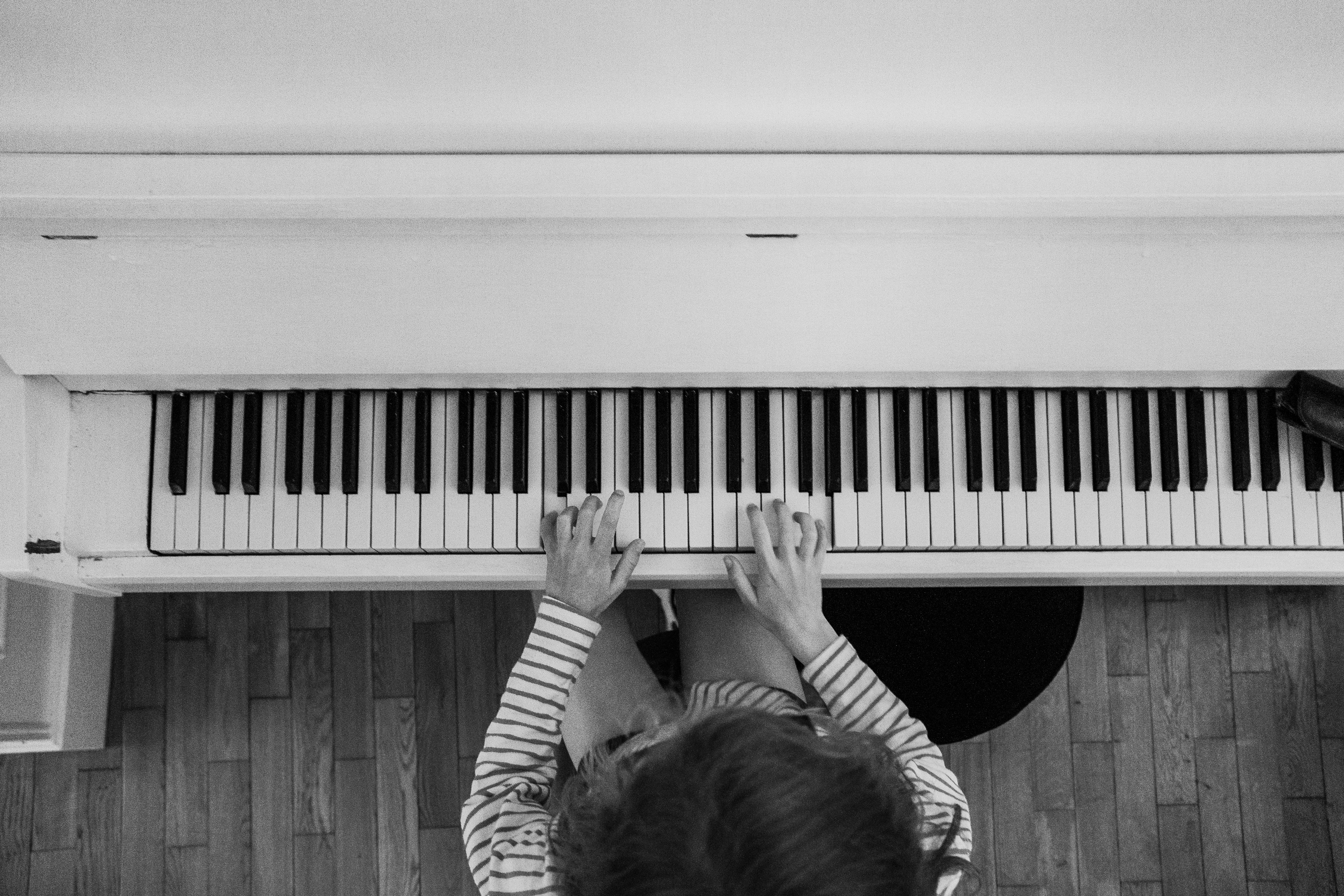 Person playing piano on wooden floor