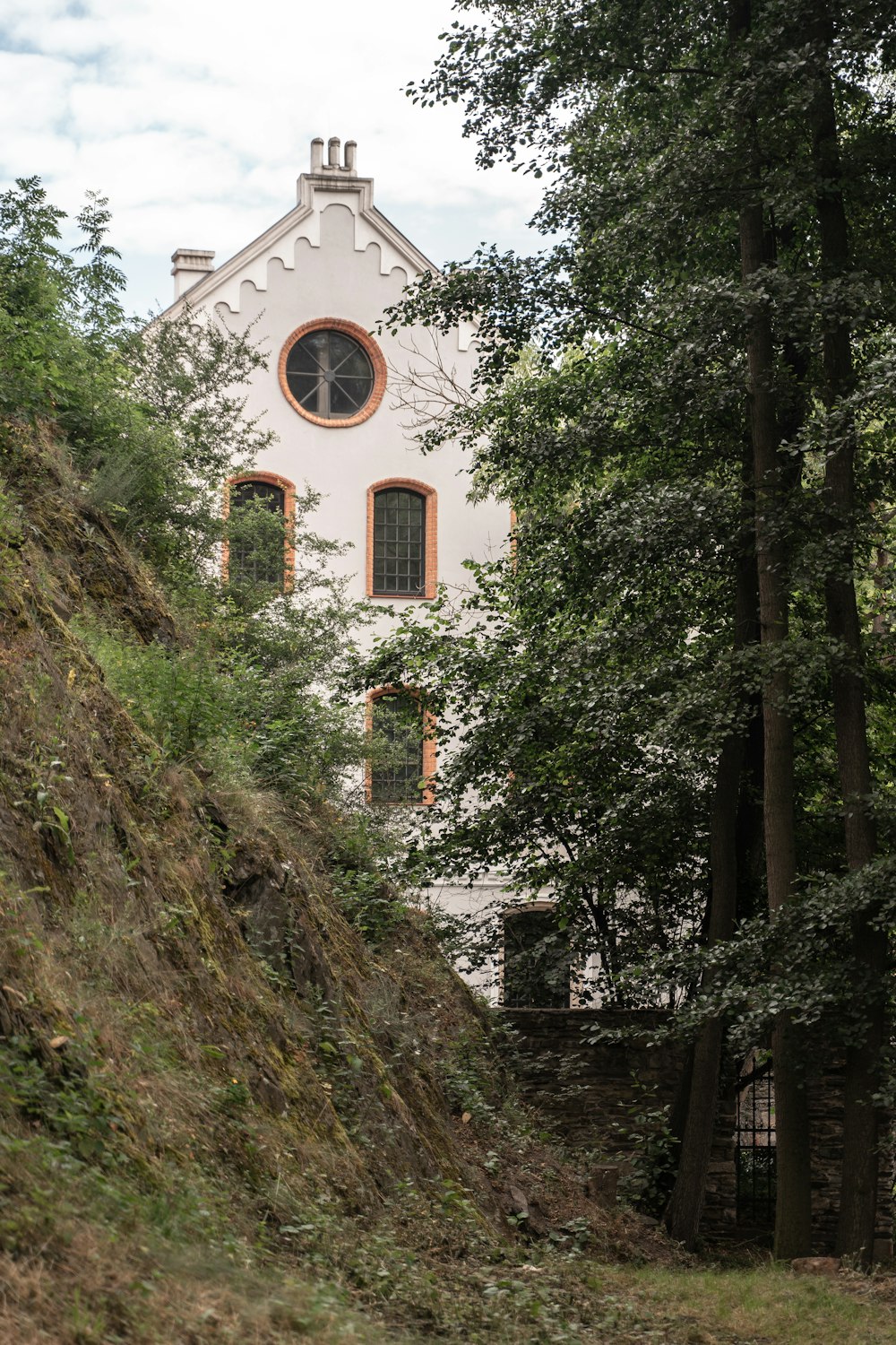 a white building with a round window on the side of a hill