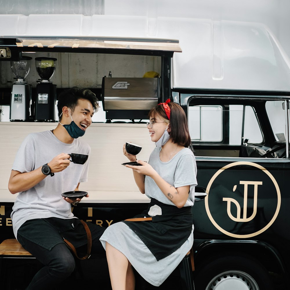 a man and a woman sitting on a bench in front of a food truck