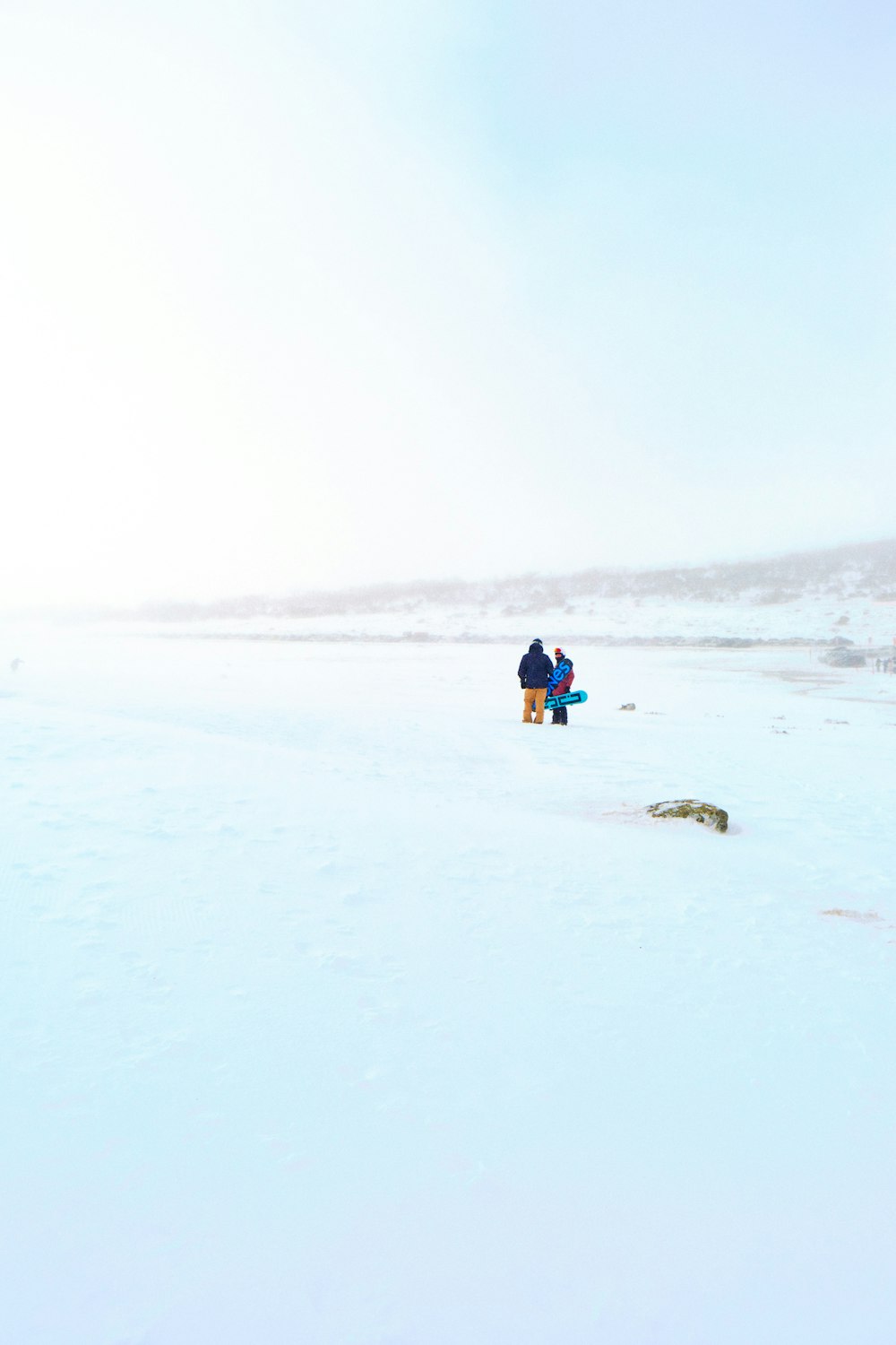 a couple of people sitting on top of a snow covered field