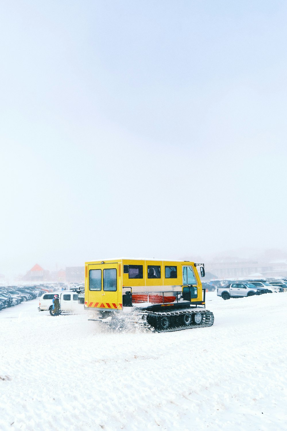 a yellow bus driving through a snow covered field