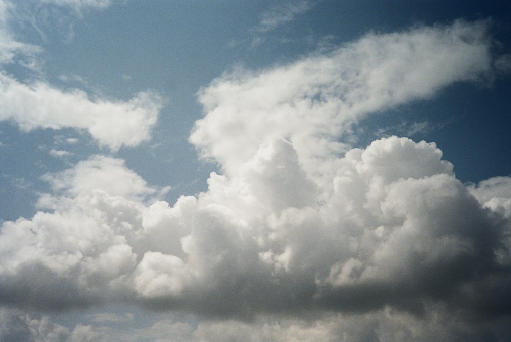 a plane flying through a cloudy blue sky