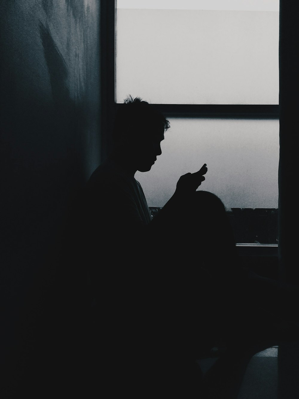 a man sitting in a dark room looking at his cell phone