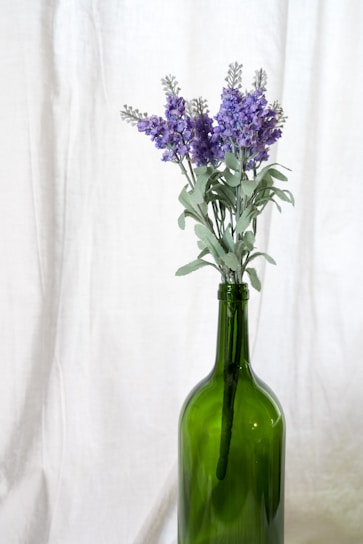 Lavender essence in a glass bottle surrounded by lavender flowers.