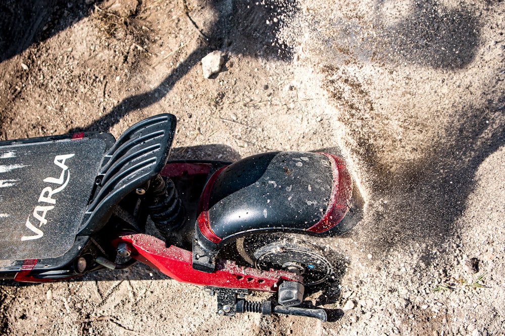 a red and black scooter sitting on top of a dirt field