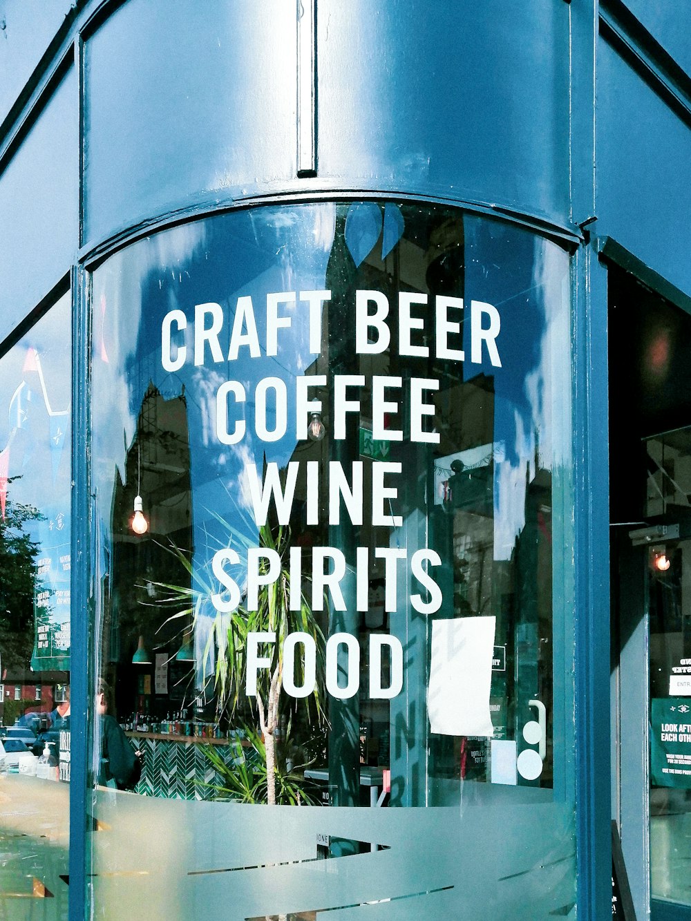 クラフトビールコーヒーワインスピリッツフードと書かれた看板のある青い建物