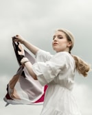 Artistic shot of a vibrant scarf flowing in the wind against an urban backdrop.