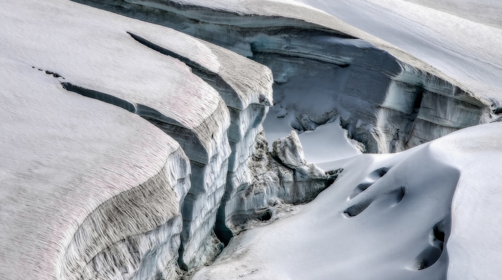 a large crack in the side of a snow covered mountain