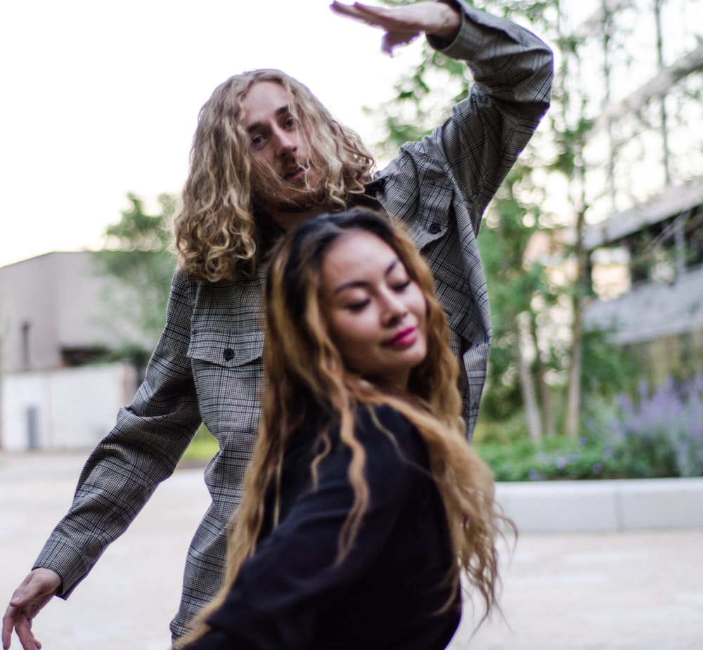 a man standing next to a woman on top of a street