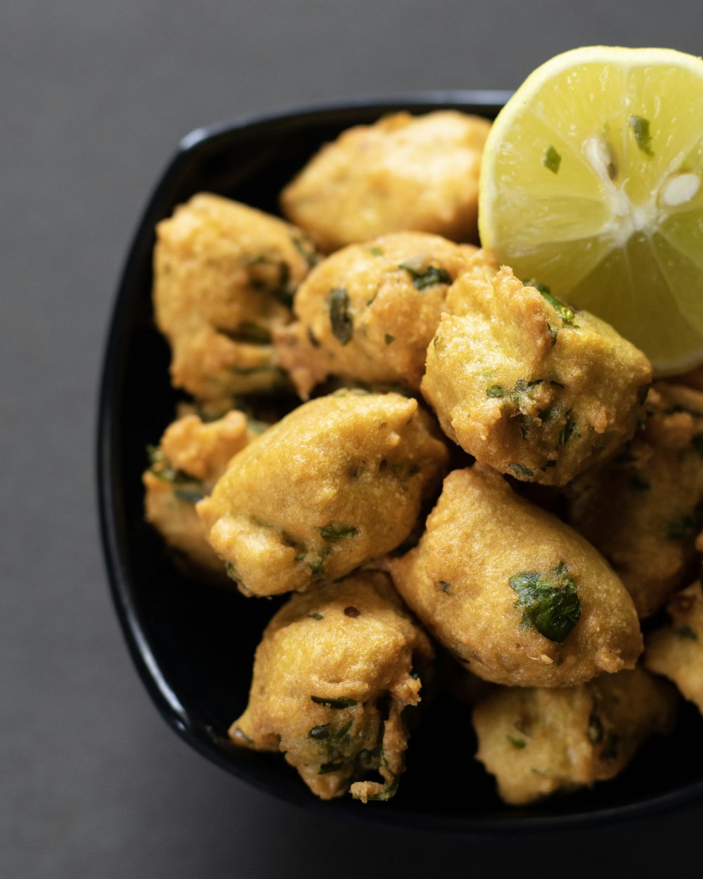 a bowl of fried food with a lemon wedge