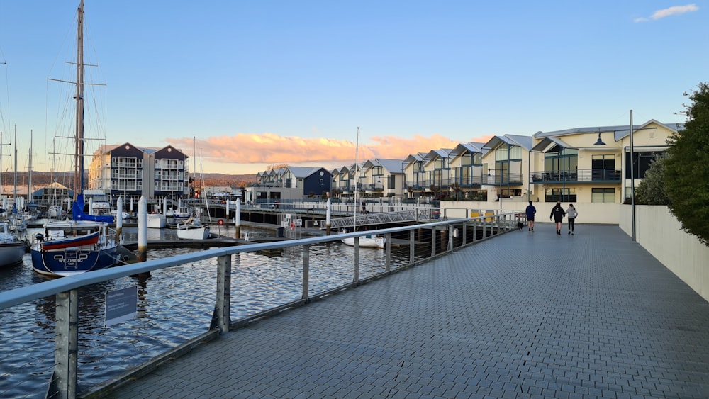 a couple of people walking down a walkway next to a body of water