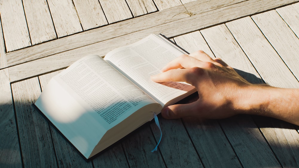 a person reading a book on a wooden deck