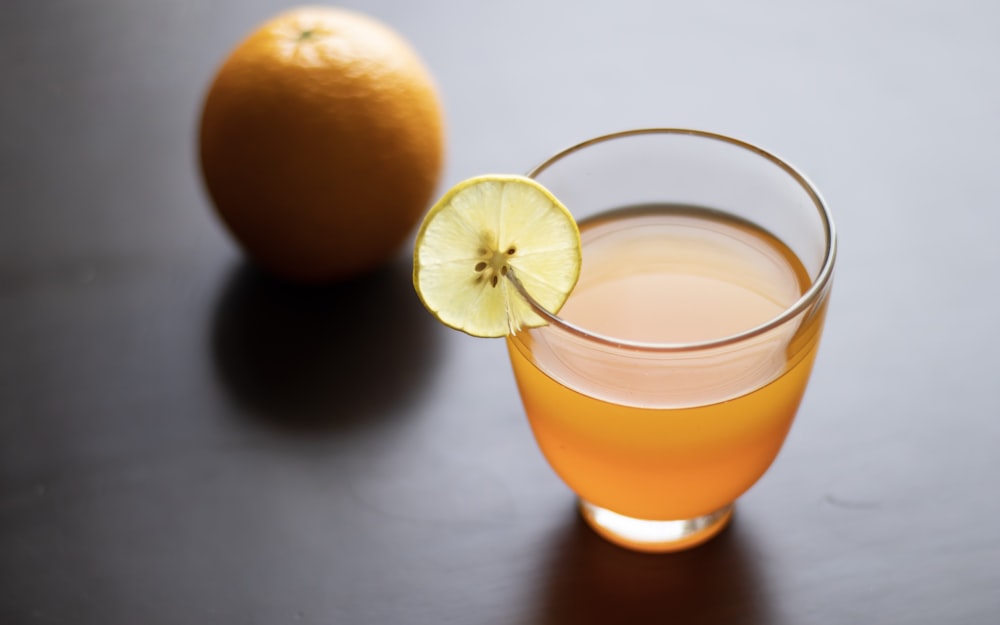 a glass of orange juice next to an orange