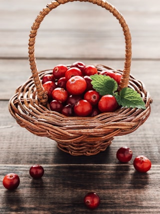 a basket filled with cherries on top of a wooden table