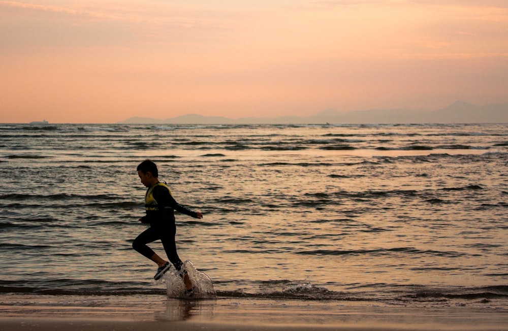 une personne courant sur la plage au coucher du soleil