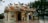 An ornate, traditional Chinese-style temple with colorful dragons and mythical creatures decorating the roof. Intricate murals and patterns adorn the exterior walls, and the temple is set in a serene environment with trees and a body of water nearby.