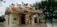An ornate, traditional Chinese-style temple with colorful dragons and mythical creatures decorating the roof. Intricate murals and patterns adorn the exterior walls, and the temple is set in a serene environment with trees and a body of water nearby.