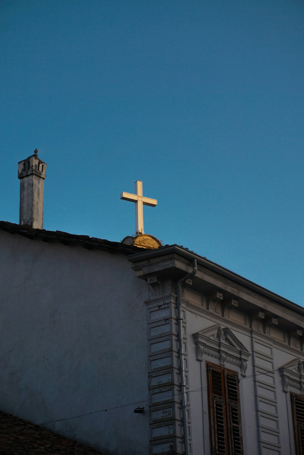 a cross on top of a building with a blue sky in the background