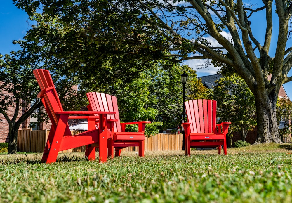 a couple of red chairs sitting on top of a lush green field