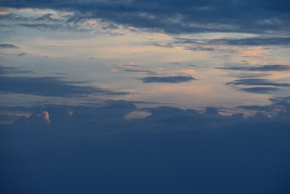 a plane flying through a cloudy sky at dusk